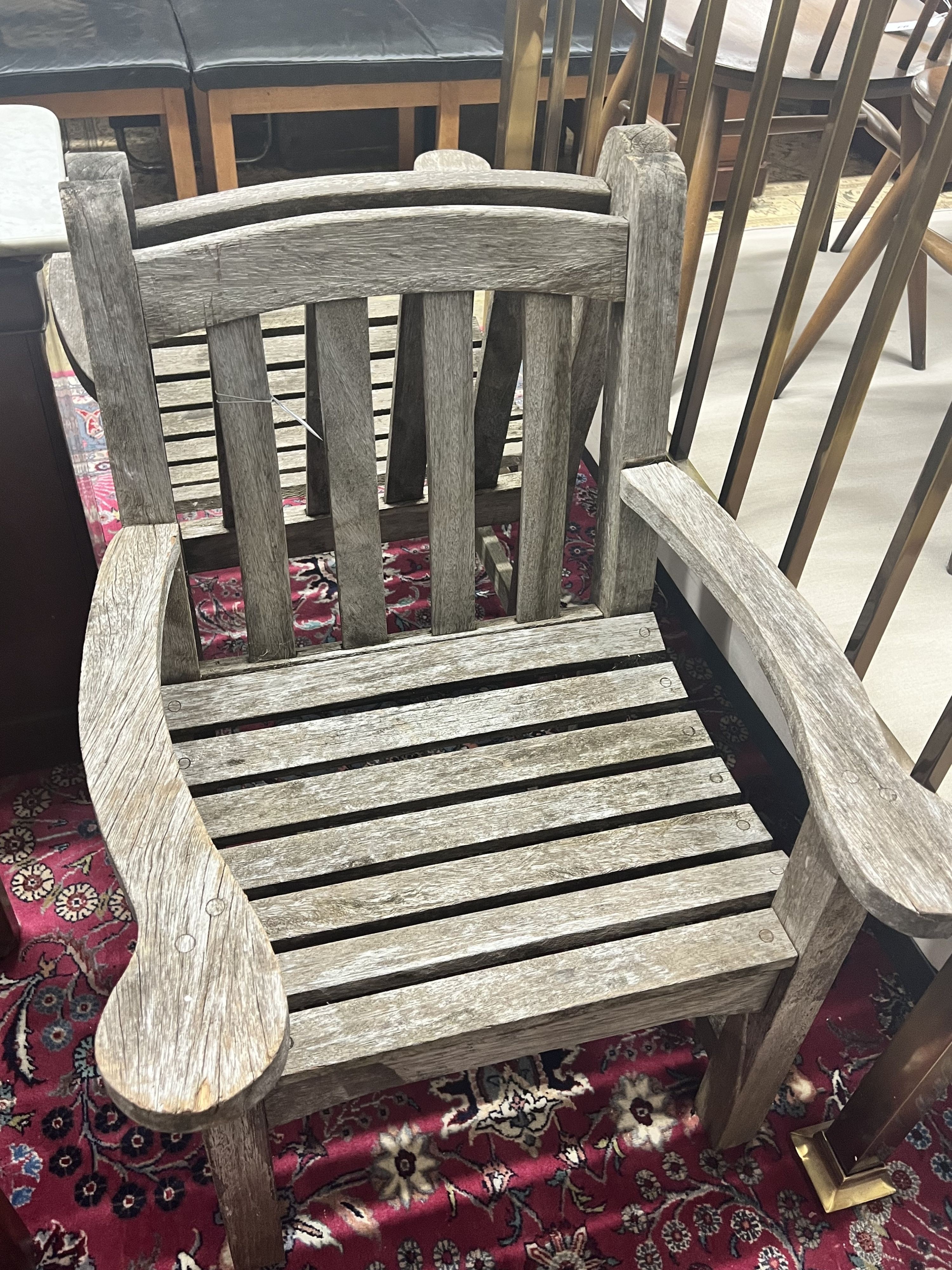 A pair of weathered teak slatted garden elbow chairs, width 64cm depth 60cm height 86cm
